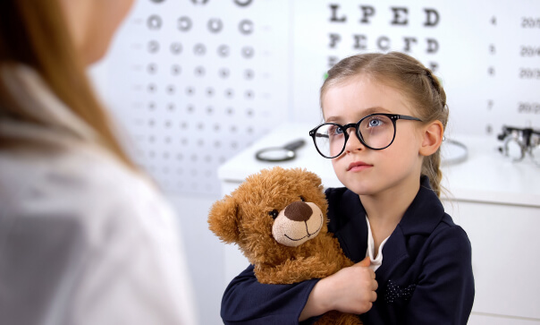 Girl wearing glasses hugging a teddy bear