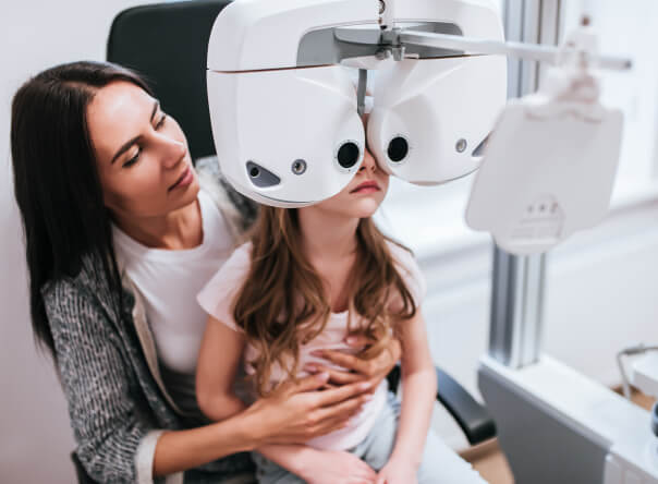 Mother assisting her daughter with her eye exam