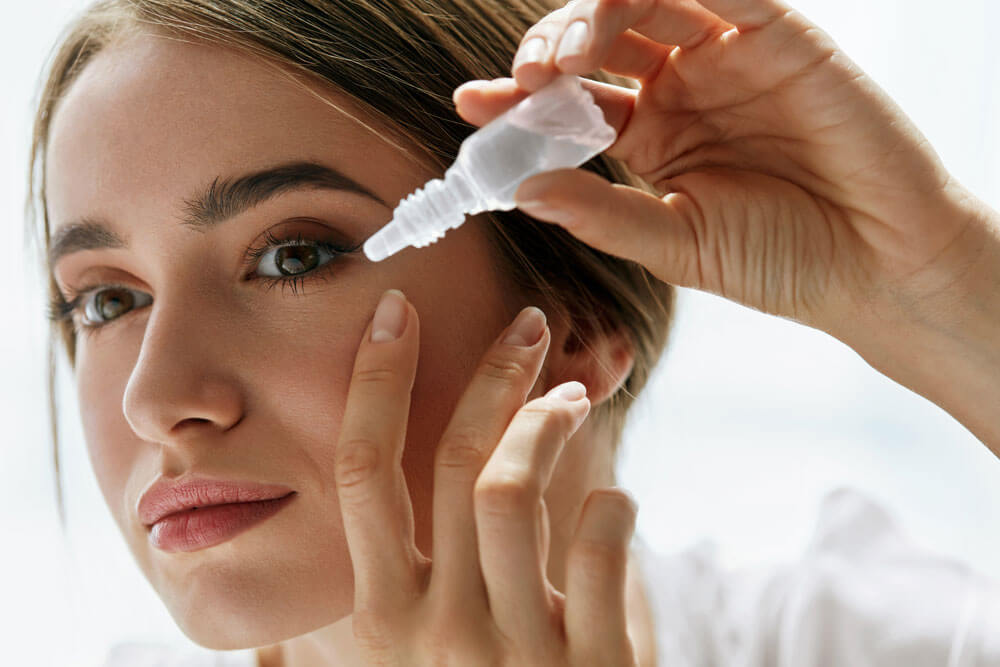 Woman applying eye drops to eyes