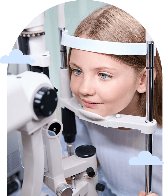 a young girl sits at an eye exam machine smiling slightly
